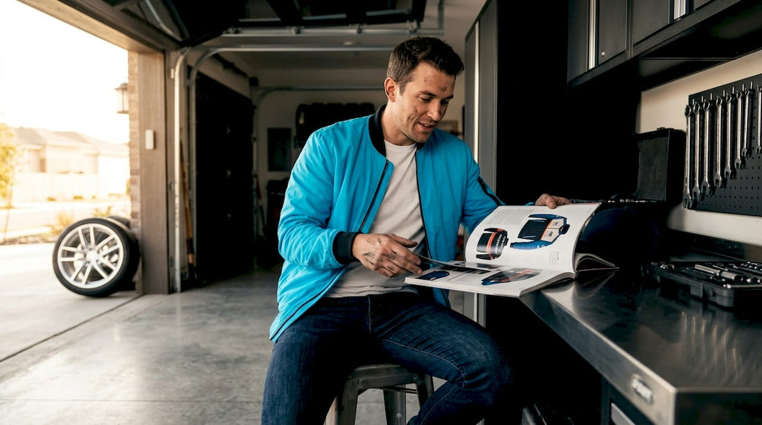 Car enthusiast reading about automotive fashion in garage